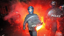 British riot police come under attack from flares as they clash with protestors during student demonstrations in Parliament Square, in London, on December 9, 2010. Angry demonstrators clashed with police in a student protest outside parliament Thursday as the coalition government faced its biggest test yet in a vote on proposals to triple university tuition fees.